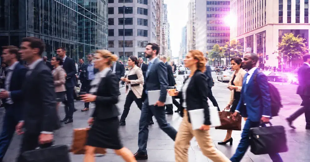 Business professionals walk across a city street while carrying briefcases