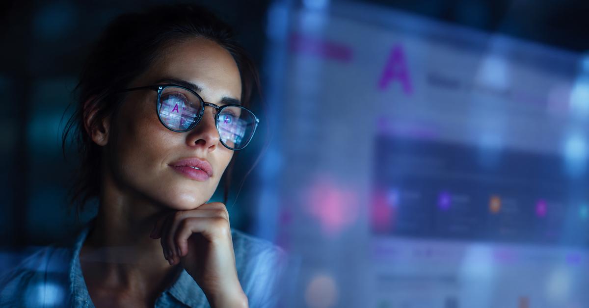 Woman wearing glasses is thinking while looking at a blurry screen
